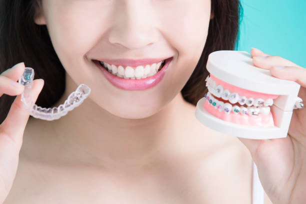 a woman holding a dental model with braces and Invisalign