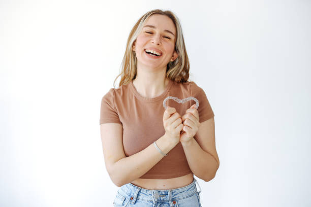 a woman holding an Invisalign forming a heart