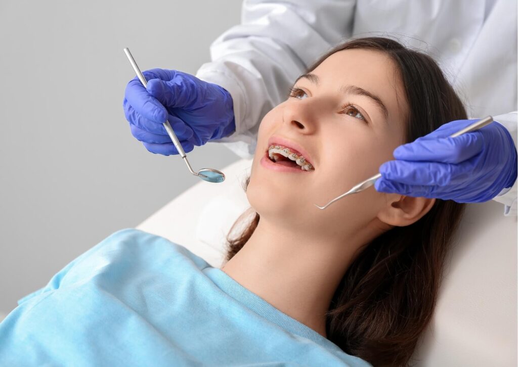 Orthodontist examining braces during a dental checkup while discussing proper orthodontic wax use for irritation relief