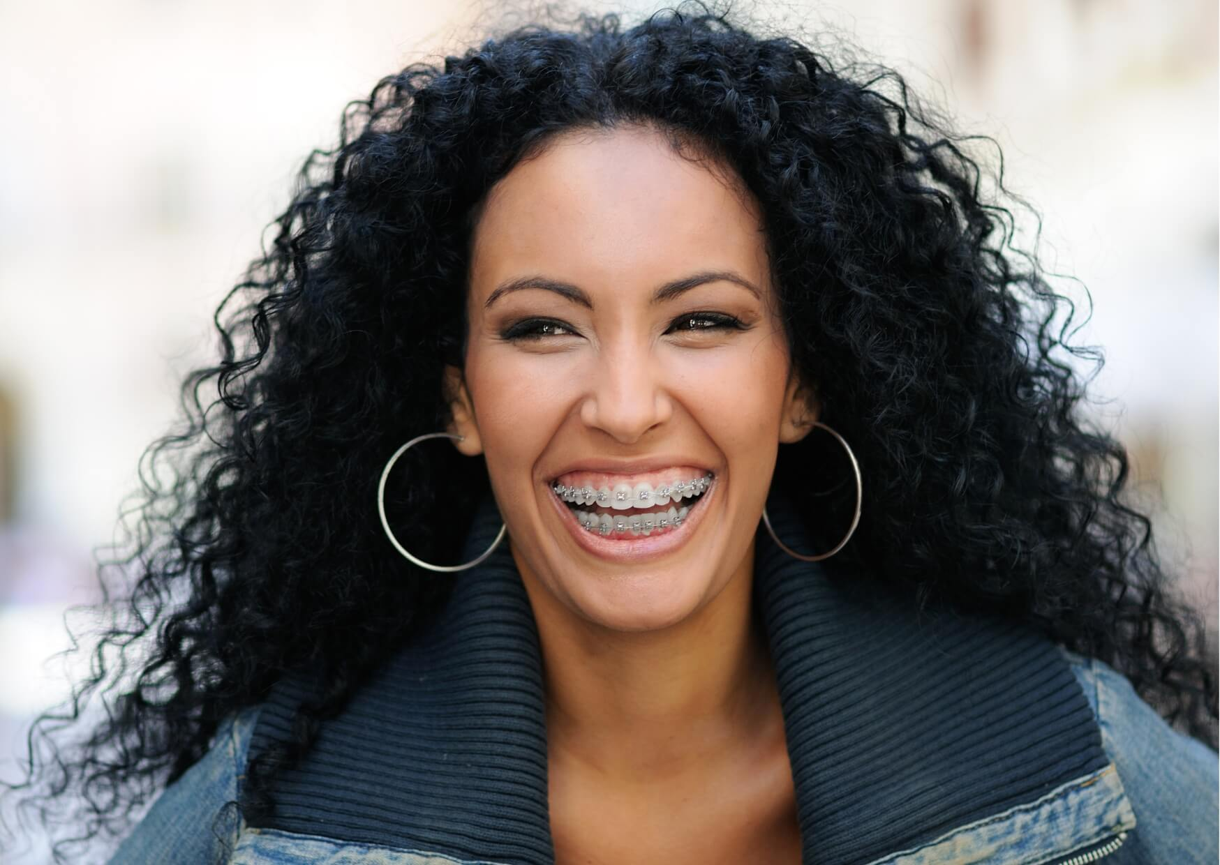 Smiling adult wearing metal braces, demonstrating that orthodontic treatment is an effective option for adults.