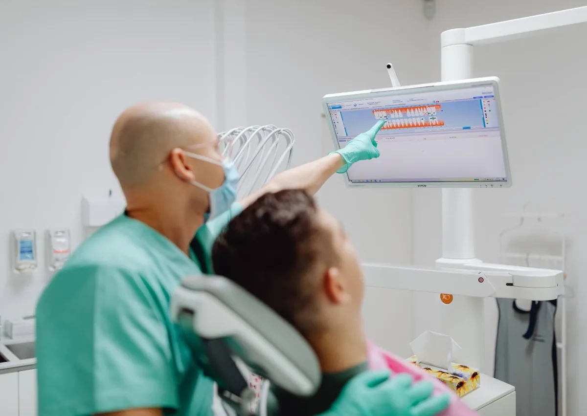 Orthodontist reviewing tooth alignment with a patient while discussing orthodontic relapse and treatment options.