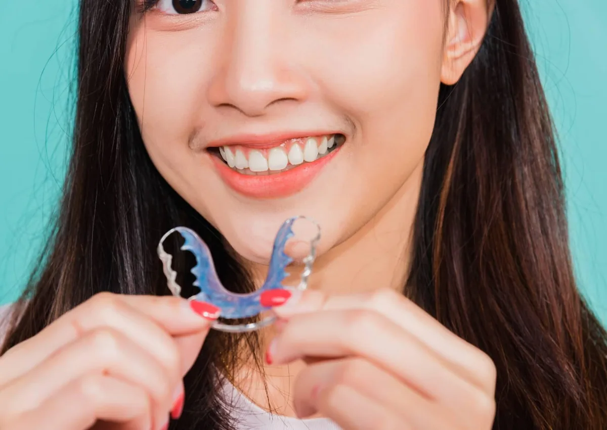 Patient holding a dental retainer used after overbite correction to help maintain proper tooth and bite alignment.