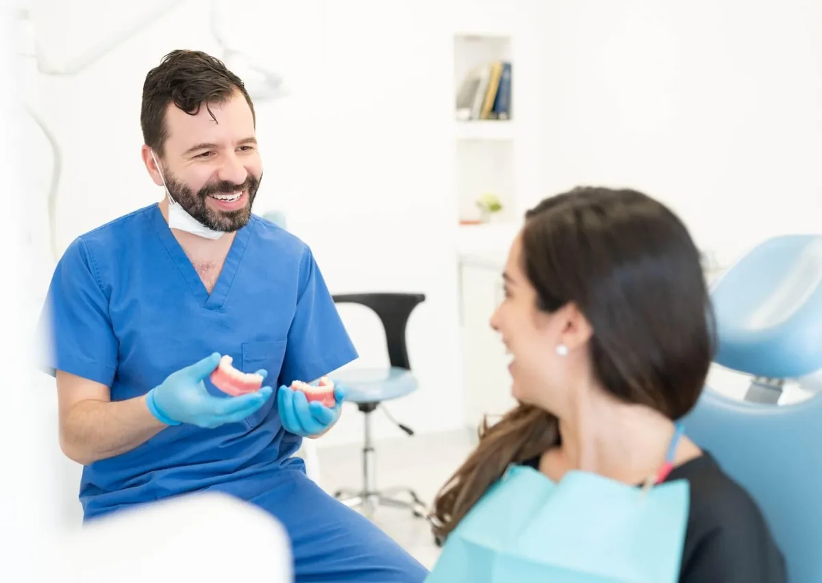 Dentist discussing overbite correction options with a patient using a dental model.